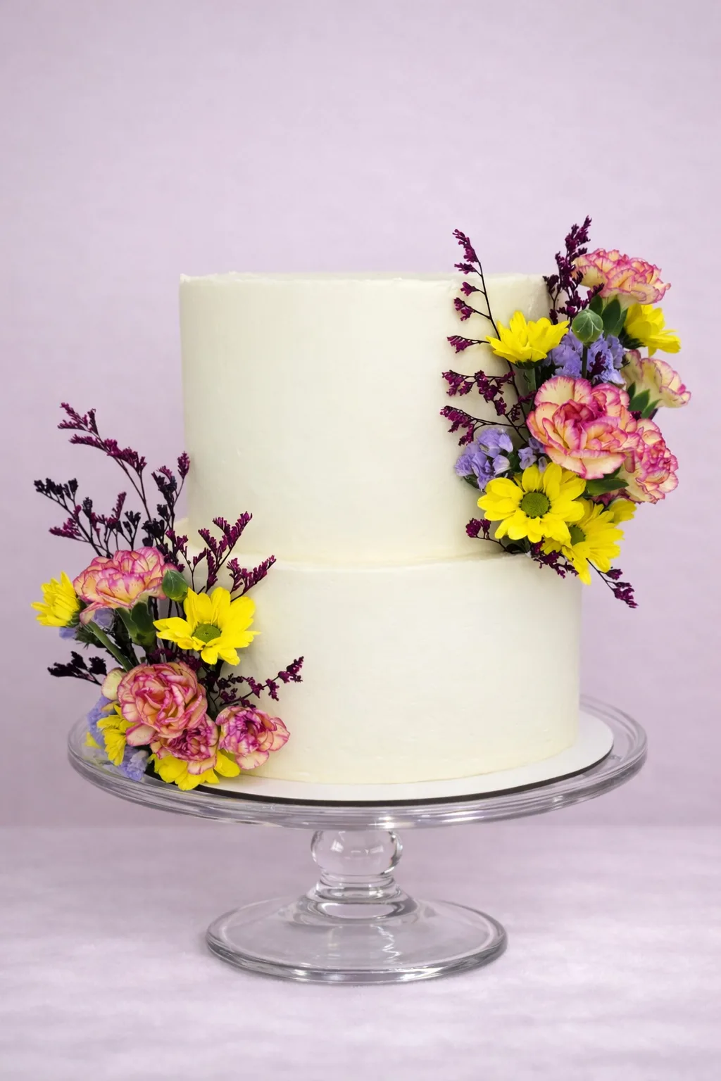 Tarta de boda de dos pisos en blanco con flores silvestres en amarillo, fucsia y lila, diseño natural y desenfadado, para bodas en Granada.