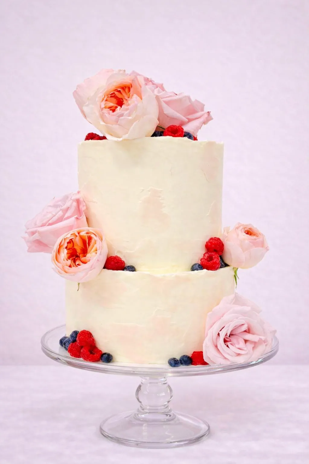 Tarta de boda de dos pisos con rosas inglesas en rosa empolvado, frambuesas y arándanos, estilo natural y romántico, para bodas en Granada.